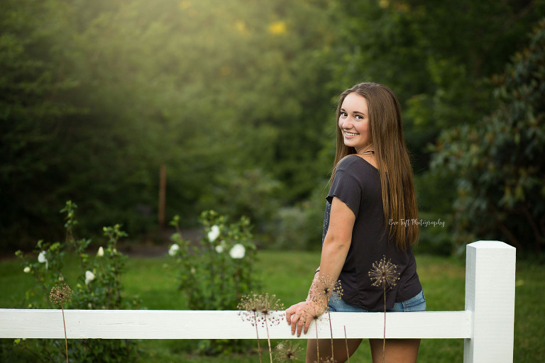 Senior girl smiling on fence in Dow Gardens. Midland, Michigan Photographer