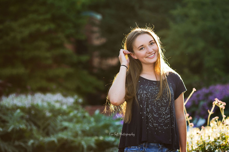 Senior Girl smiling while tucking hair behind her ears at Dow Gardens. Midland, Michigan photographer