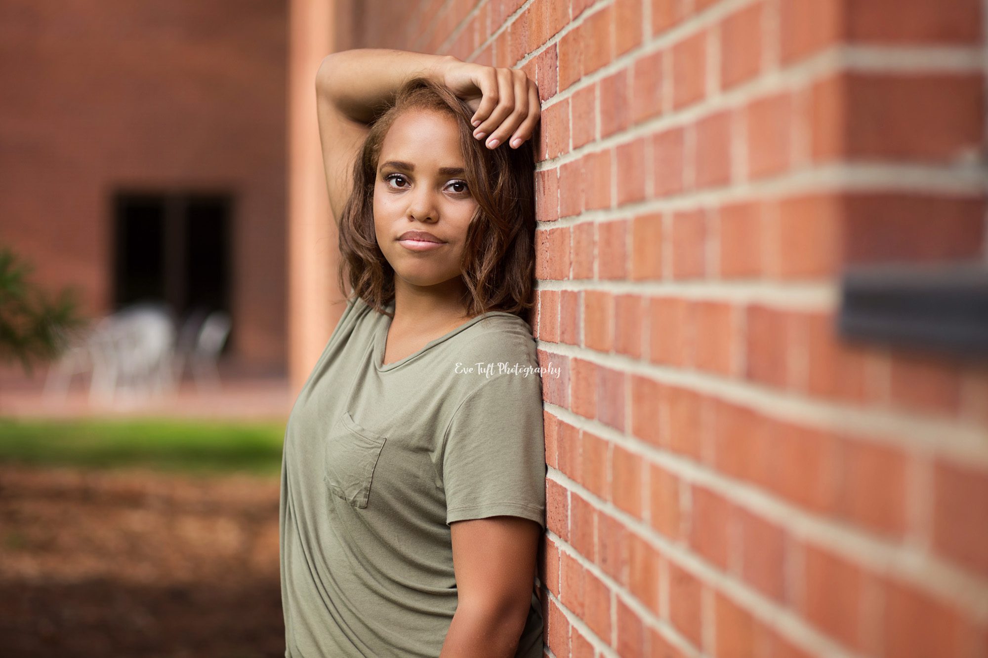 High School girl leaning against a brick wall with her arm raised above her head | Michigan Photographer in Midland and Bay City