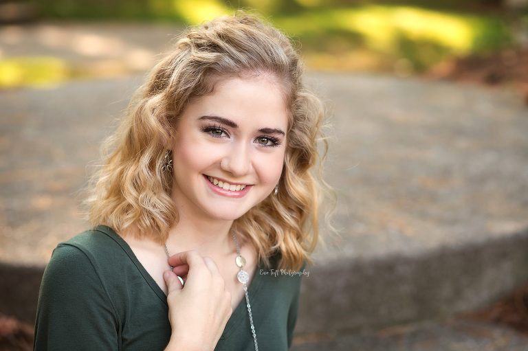 Smiling blond senior touching her necklace. Midland, Michigan photographer