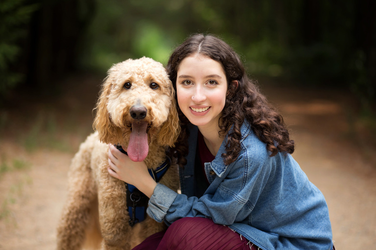 A senior girl crouches down next to her dog at City Forest | Midland, Michigan Senior Photographer