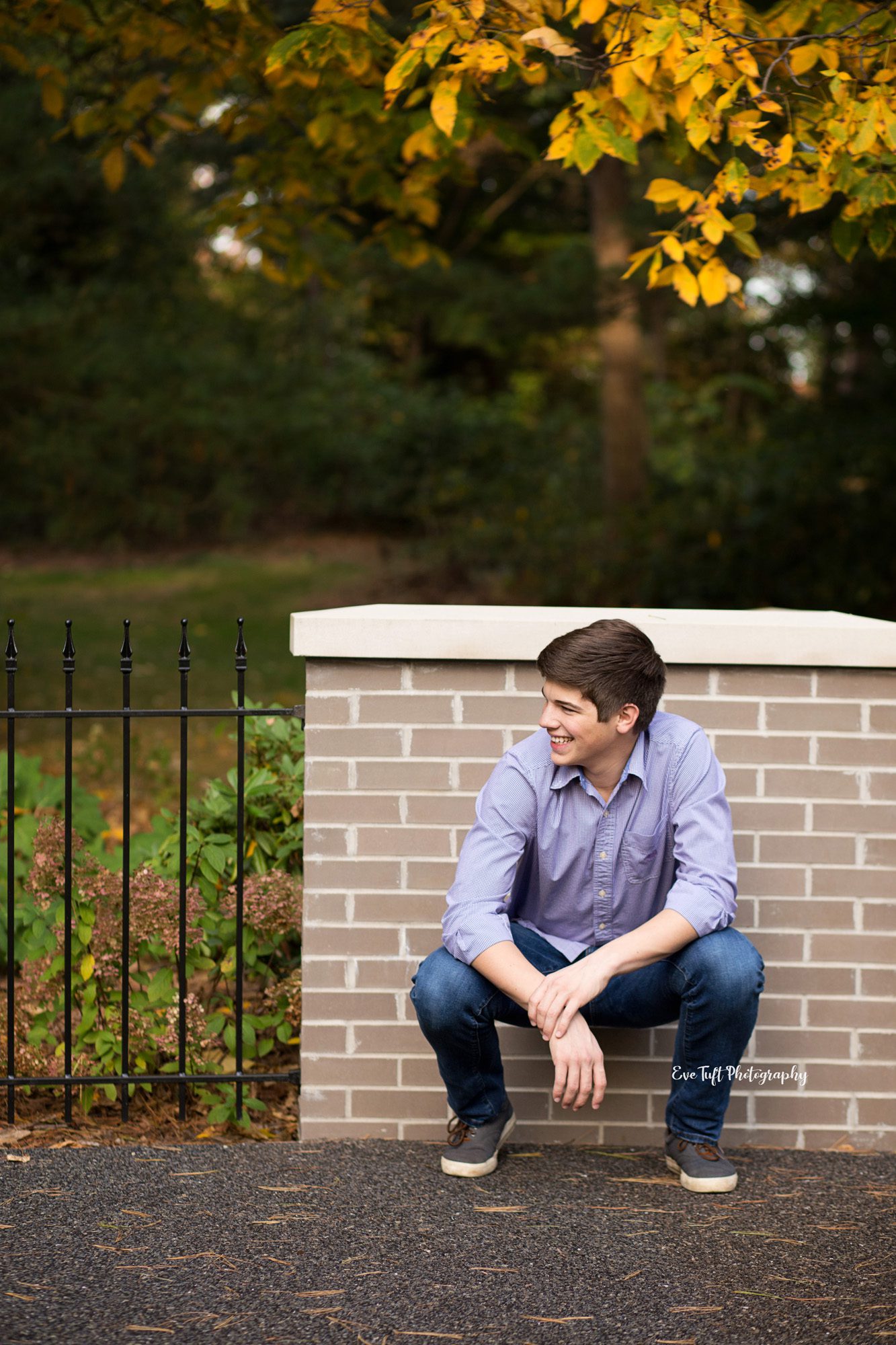 Senior session in the fall with boy crouched down looking to the side. Midland, Michigan photographer