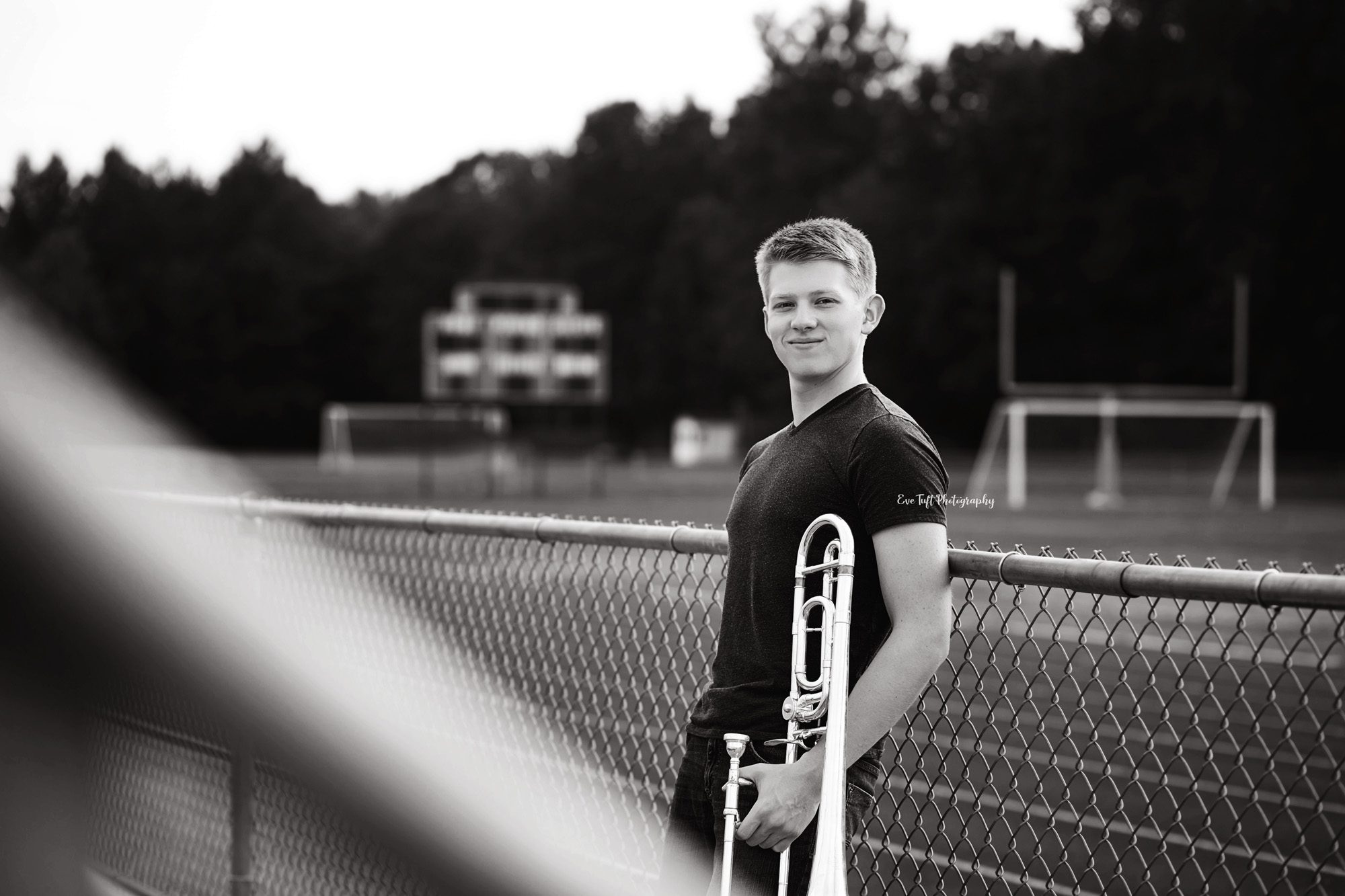 Senior guy holding his trombone by the bleachers. Midland, Michigan photographer