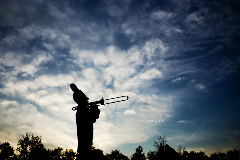 Silhouette of a senior boy playing the trombone with a sky full of clouds | Michigan Senior Photographer