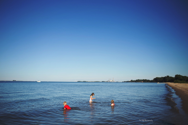 Three children playing in the water in a lake. Midland Michigan photographer