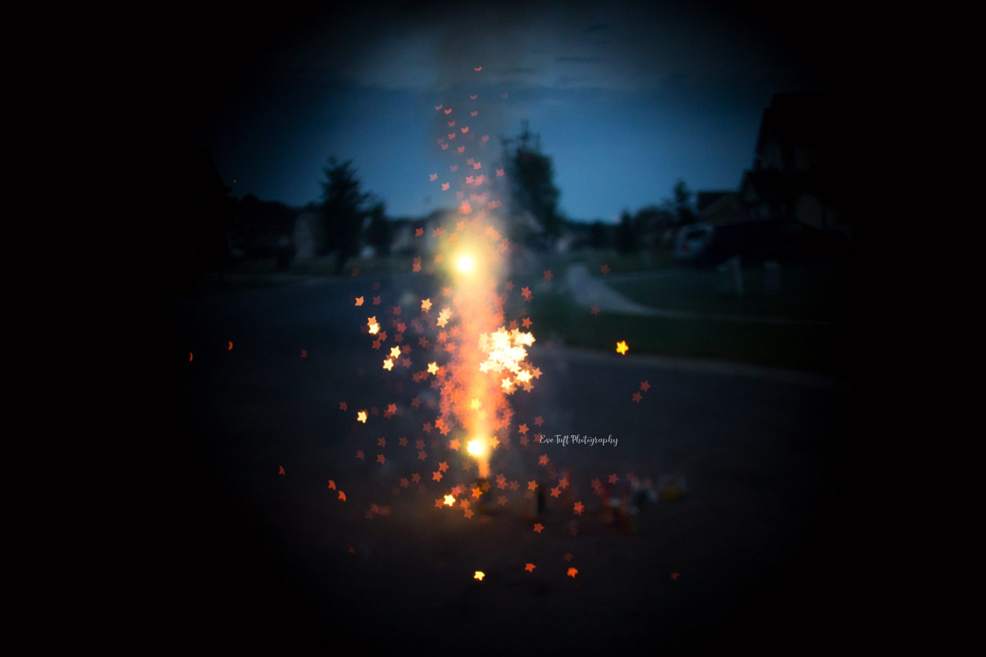 Star shaped bokeh fireworks in front of a house on the fourth of July. Midland, Michigan photographer