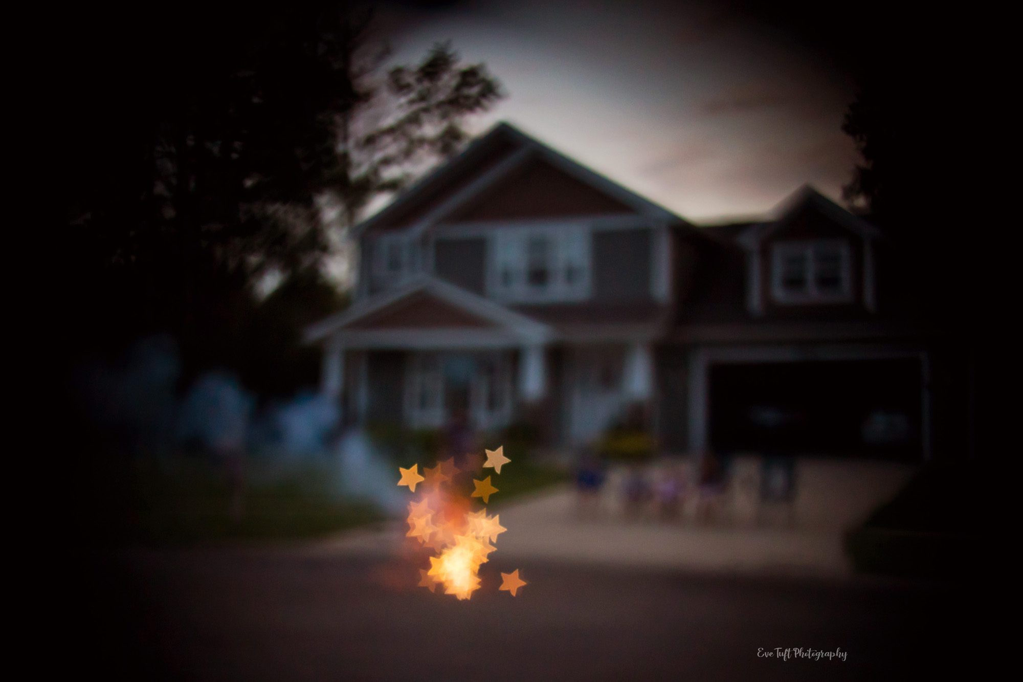 Star shaped bokeh fireworks in front of a house on the fourth of July. Midland, Michigan photographer