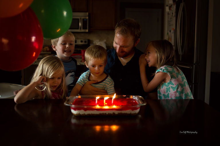 Father and four children sitting at the table before dad blows his candles out on his birthday. Midland, Michigan Photographer