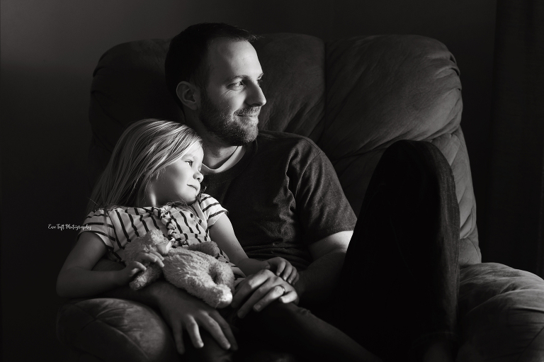 Little girl sitting on her father's lap on a rocking chair inside. Michigan photographer