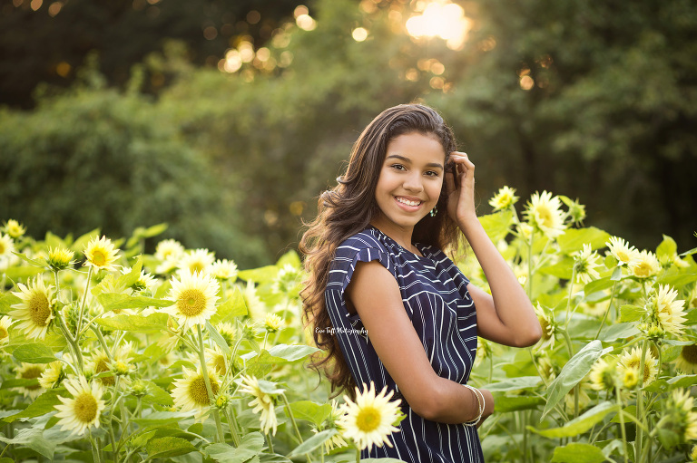 Senior girl standing in a field of sunflowers smiling. Michigan photographer