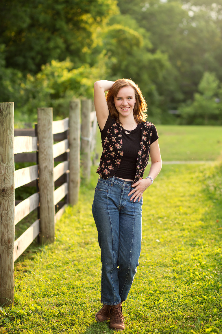 Senior girl standing and posing by a wooden fence. Chippewa Nature Center in Midland