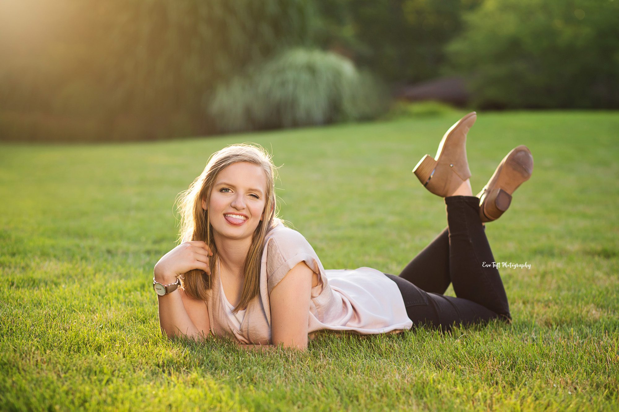 Senior girl lying in the grass at Dow Gardens making a fun face. Midland photos