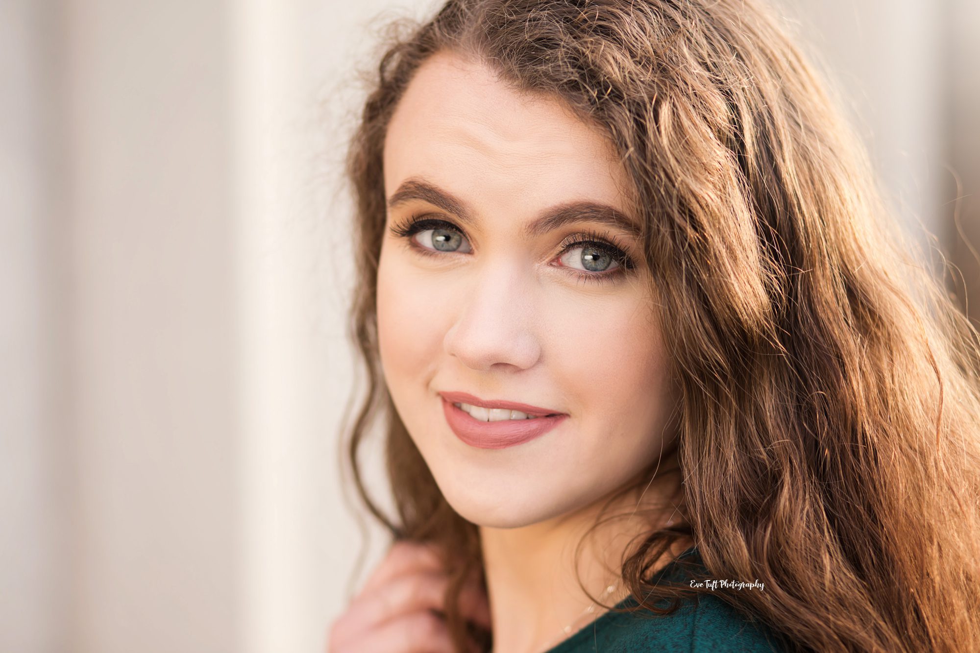 Close up of a senior girl with brown hair with her hand in her hair | Michigan Portrait Photographer