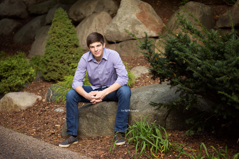 A senior boy sitting on the edge of a rock in Dow Gardens | Midland, Michigan Photographer