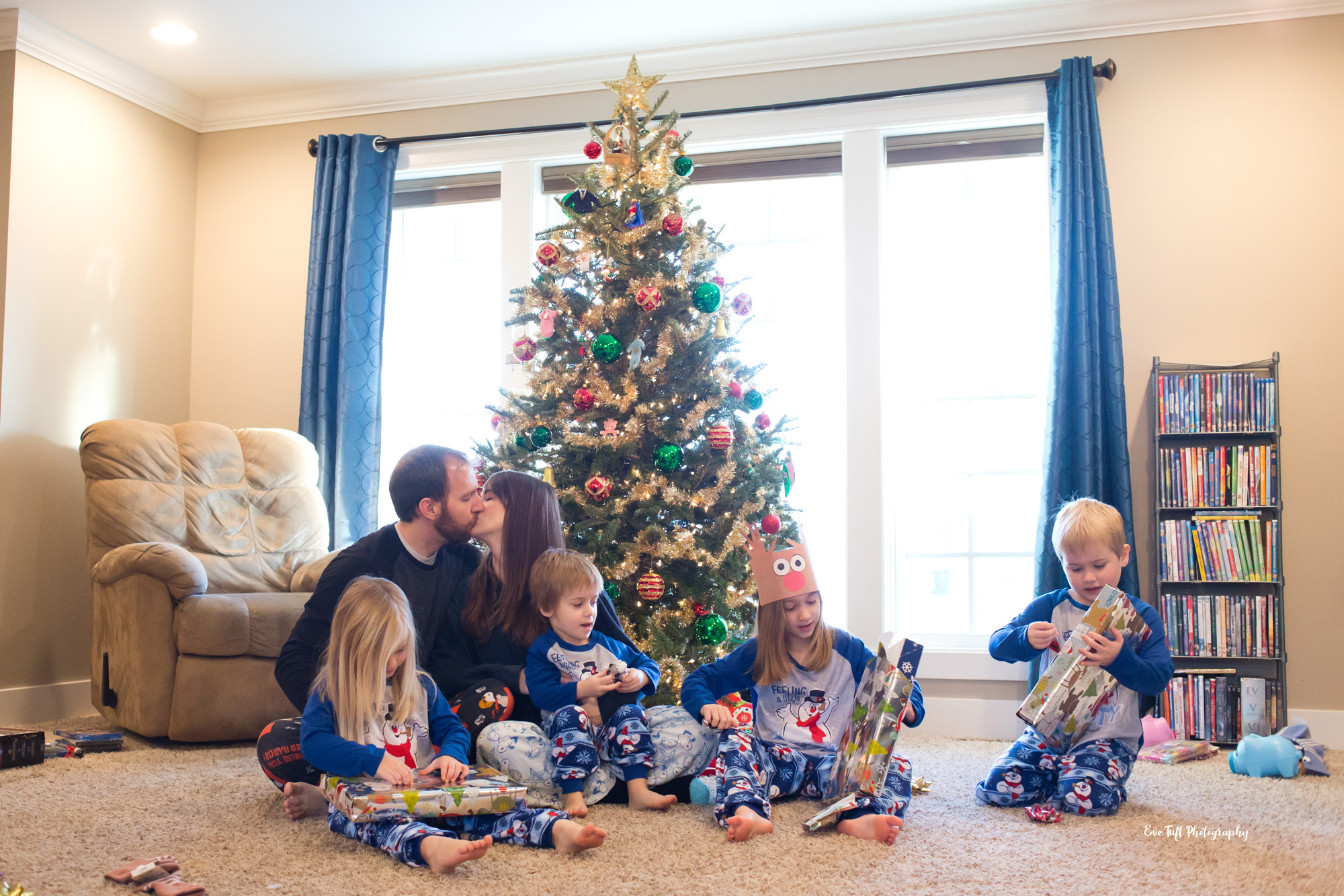 A loving family around the Christmas tree in their home opening up presents | Eve Tuft Photography | Michigan Photographer