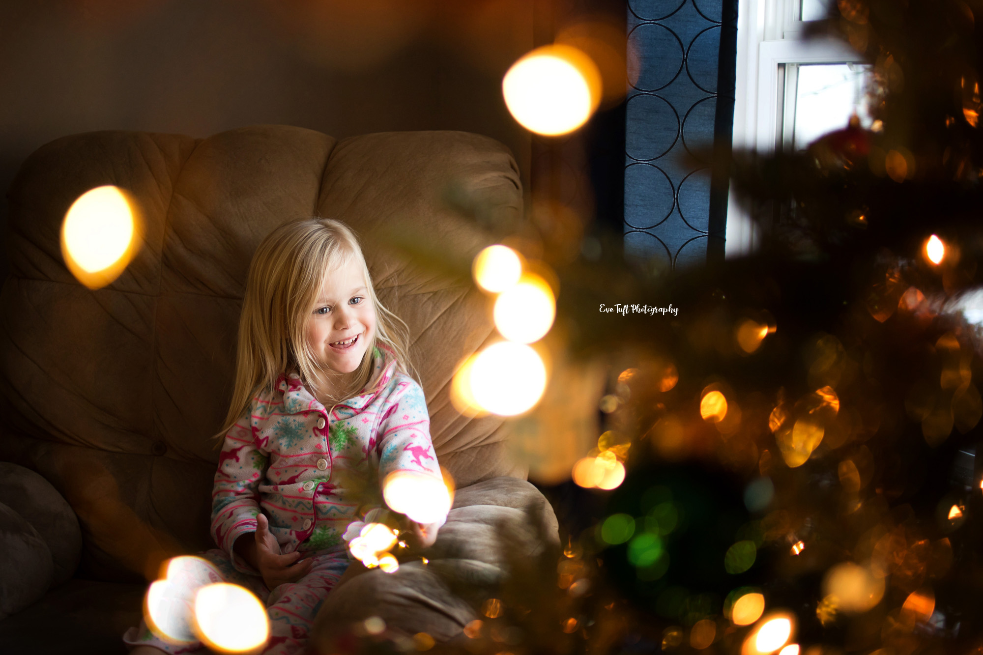 Little girl happily looks at a Christmas tree inside at Christmastime | Saginaw Senior Photographer | Eve Tuft