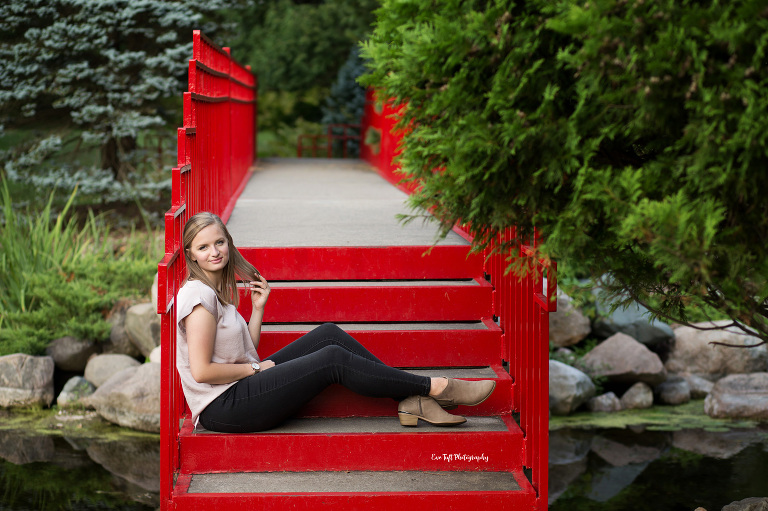 Senior girl sitting on a red bridge at Eve Tuft Photography's Favorite Location of Dow Gardens