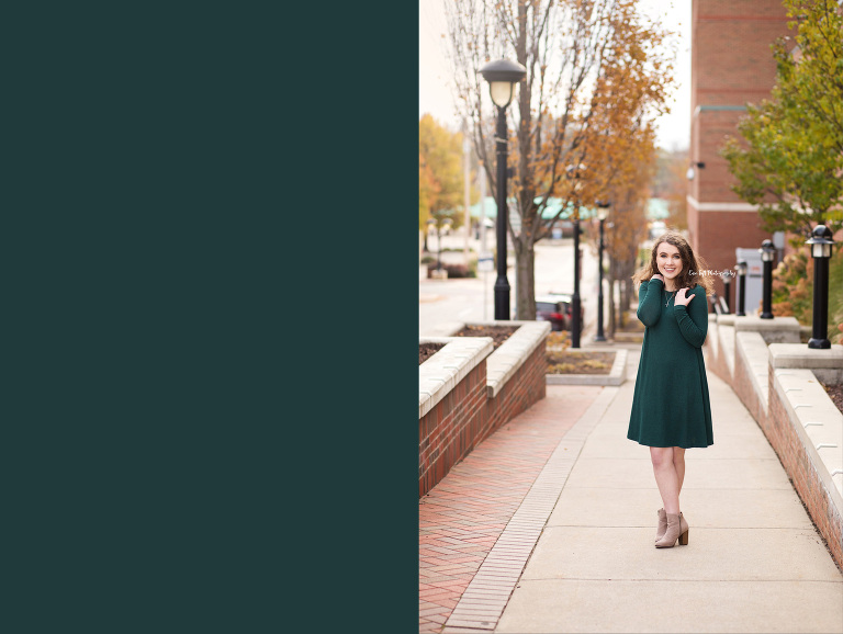 A high school girl in a green dress standing on the sidewalk in a downtown area in Michigan | Midland High School Photographer