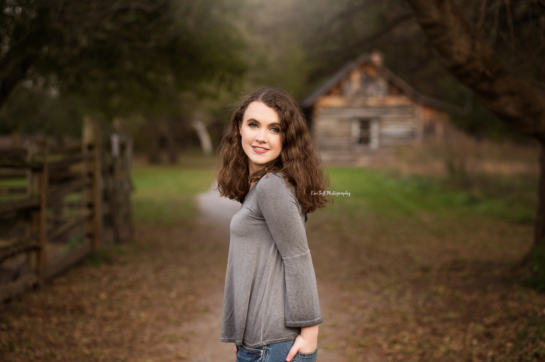 Senior girl standing outside with a barn in the background | Midland, Michigan photographer for seniors and high school teenagers