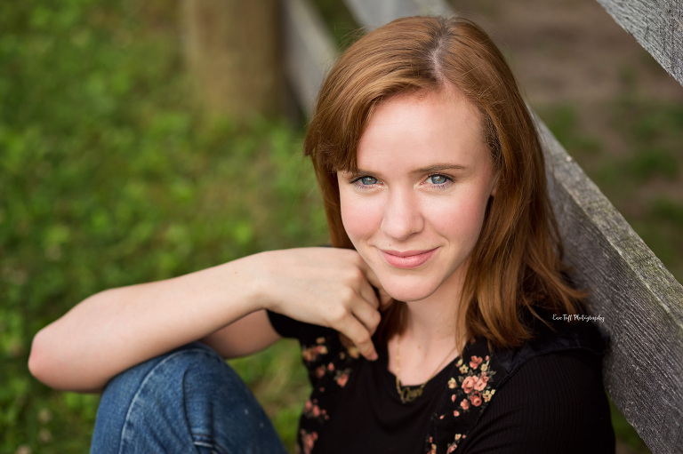 Red-headed senior girl posing next to a fence at the location of the Chippewa Nature Center | High School Photographer in Michigan