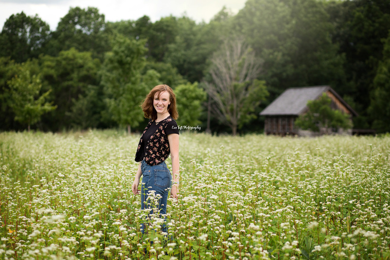 High School girl standing in a field of wildflowers with a barn in the background at the Chippewa Nature Center in MidMIchigan | Senior Photographer