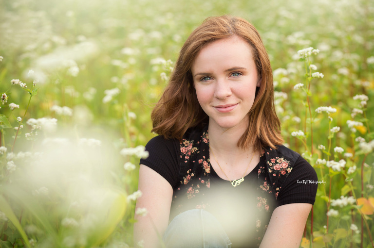 A red-head teenager sitting in a field of wildflowers for her senior photos | Michigan Portrait Photographer 