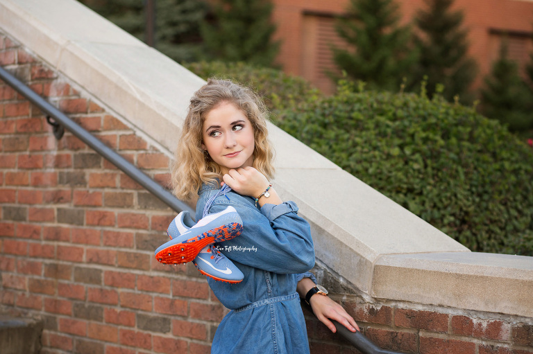 A high school senior holding a pair of shoes across her shoulder for her senior pictures | Midland, Michigan photographer