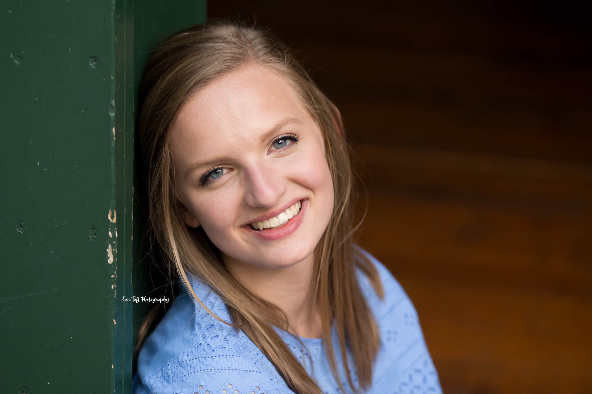 Senior girl with blue eyes and a blue shirt smiling up at the camera | Michigan high school photographer