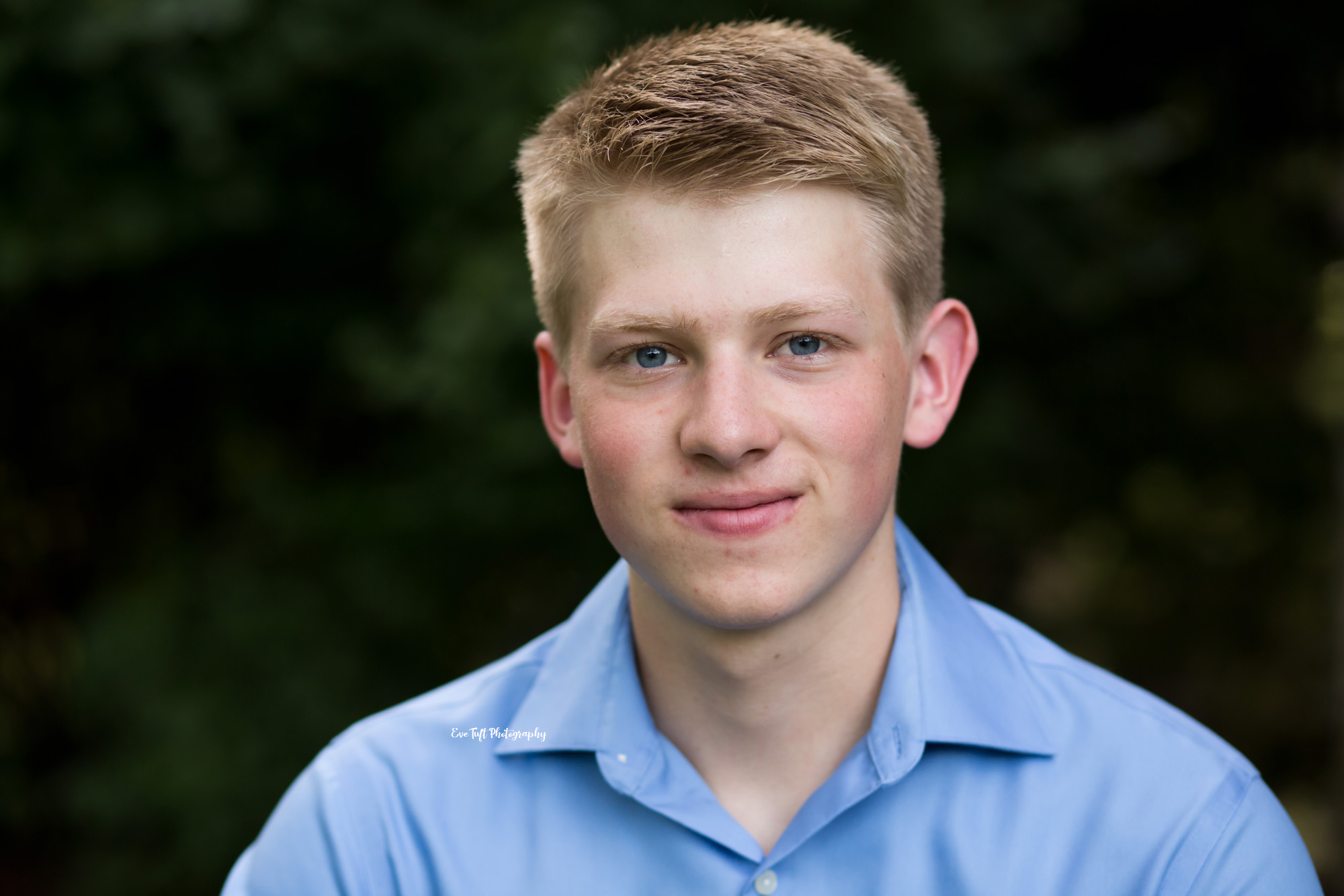 Senior boy in a blue shirt smiling at the camera | Michigan high school photographer