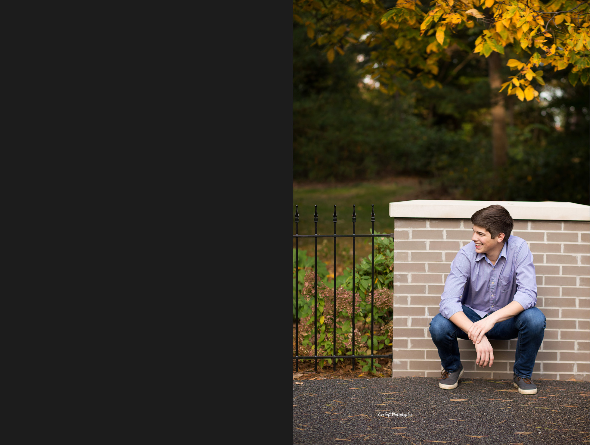 Senior boy crouching down and looking away from the camera while smiling | Michigan Photographer