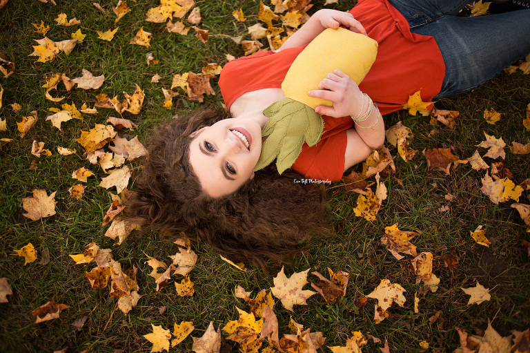 Senior girl lying on the ground with fall leaves for her photography session