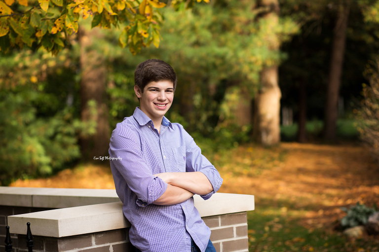 Senior boy leaning against a wall with his arms crossed | Senior photographer in Midland, Michigan