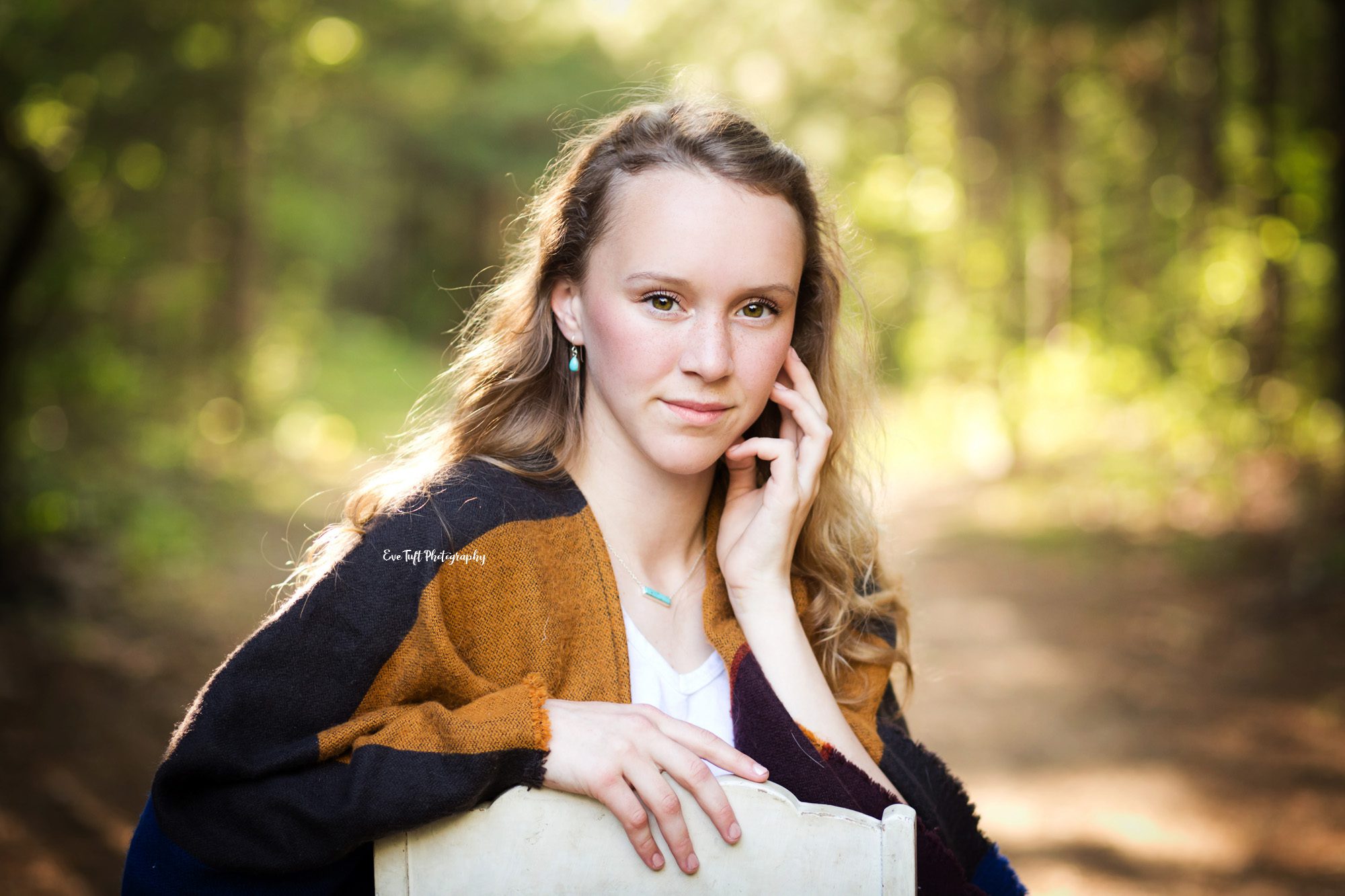 Close up shot of a senior girl sitting on a chair outside in a forest with Eve Tuft Photography, a senior portrait photographer