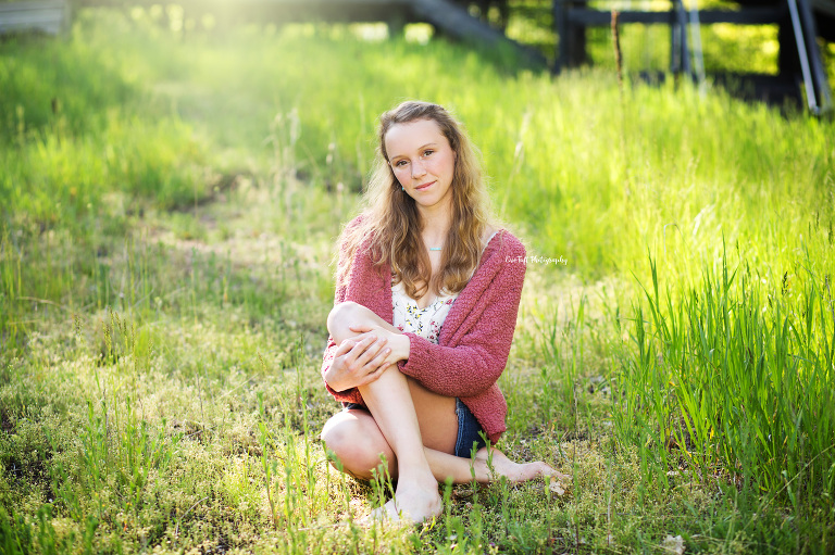 Eve Tuft Photography's first senior of the year session with a girl sitting in the grass holding one knee