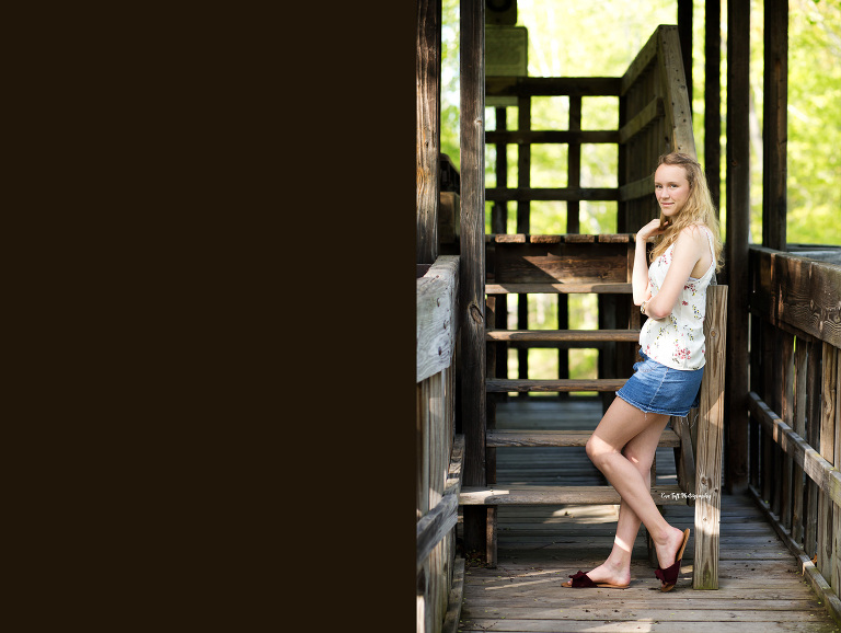Senior girl standing up and leaning against stair railings outside in Midland, Michigan | Photographer for senior portraits