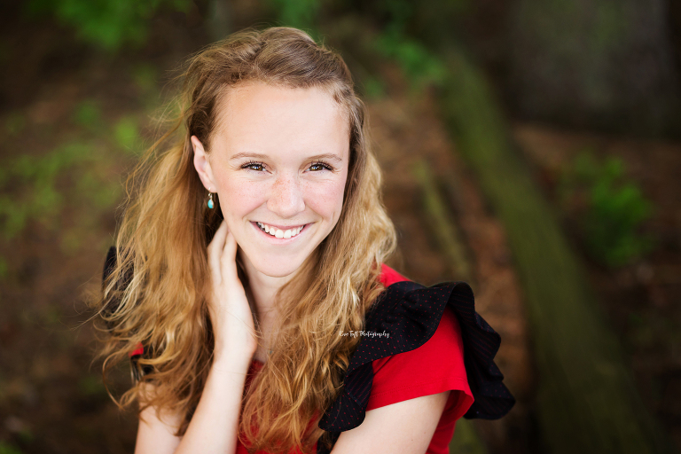 Senior girl smiling at the camera outside with her hand behind her neck | Freeland, Michigan Senior Photographer