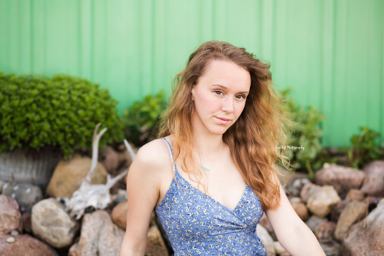 Senior girl sitting in front of a green bar and some rocks | Senior Photographer in Michigan