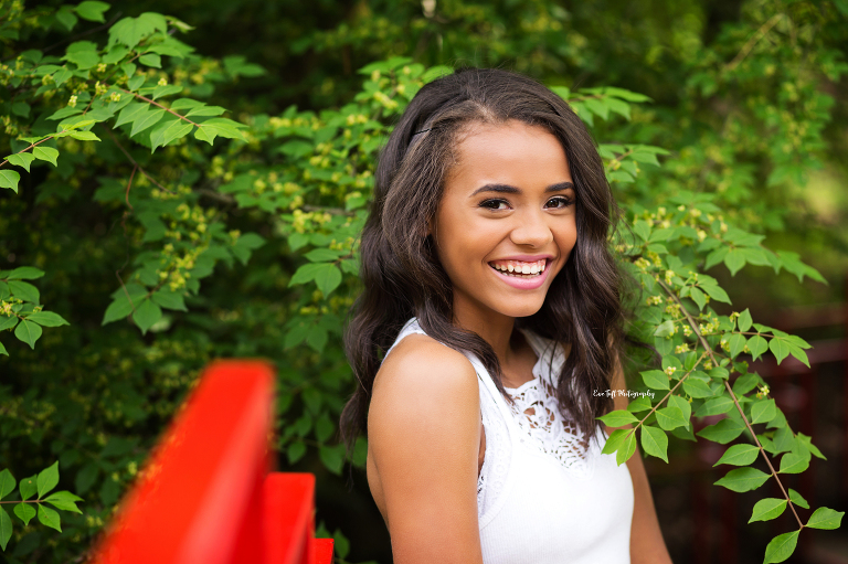 Senior girl laughing outside next to a red bridge for an Instagram giveaway | Midland, Michigan Senior Portraits
