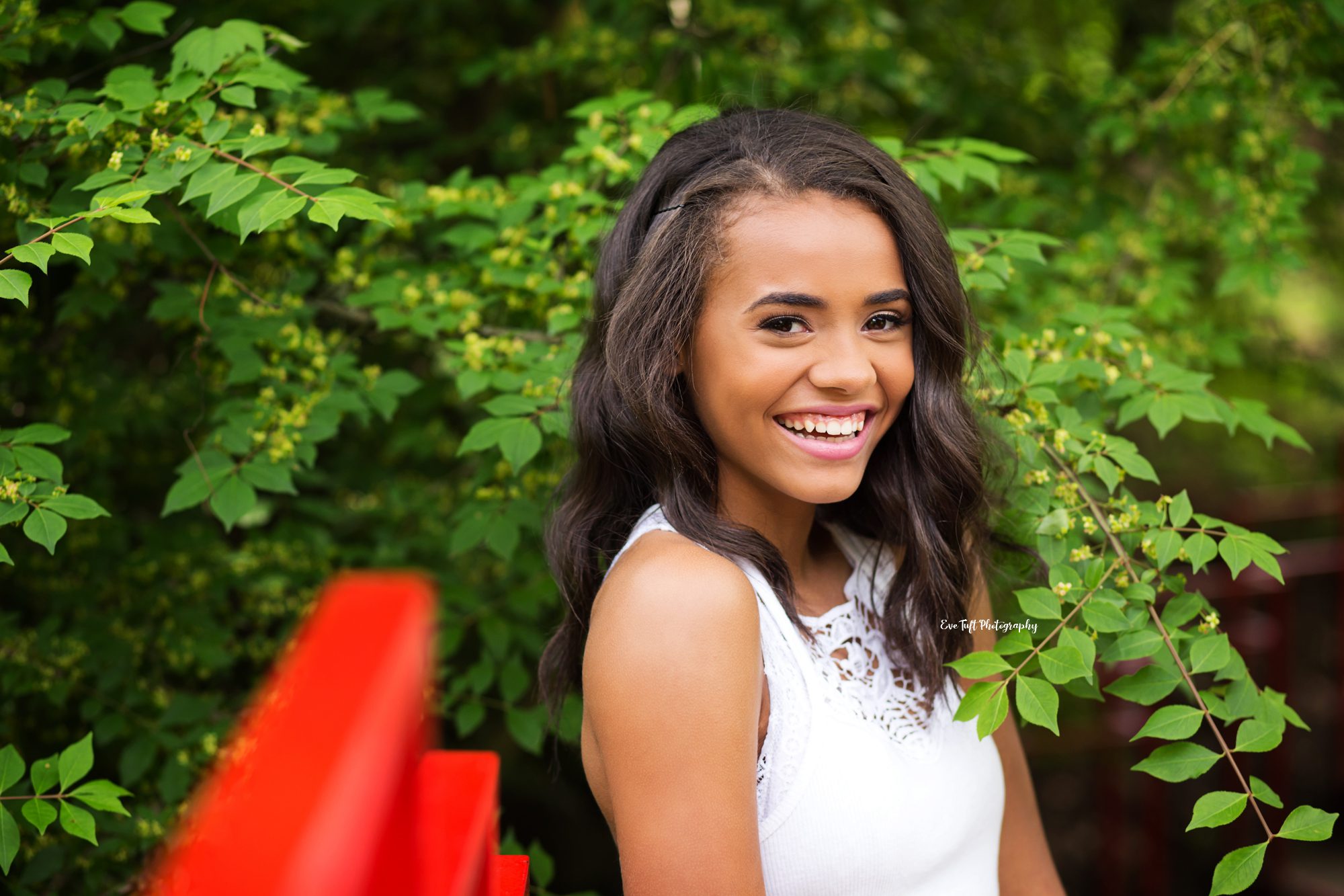 Senior girl laughing outside next to a red bridge for an Instagram giveaway | Midland, Michigan Senior Portraits