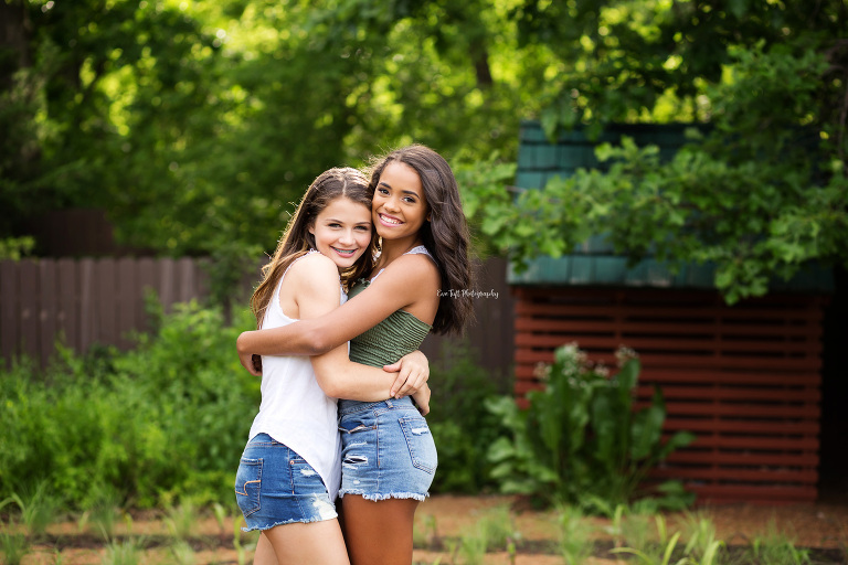 Two high school girls who are best friends hugging each other outside in Dow Gardens in Midland, Michigan