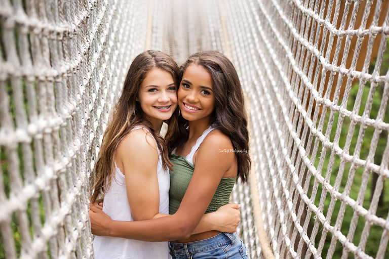Two best friends hugging each other in the middle of a rope swing outside at Whiting Forest in Midland, Michigan | Senior Photographer