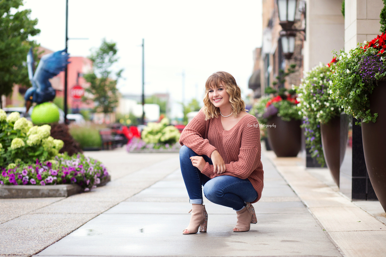 Senior girl squatting outside in an urban location in Midland, Michigan | Portrait Photographer