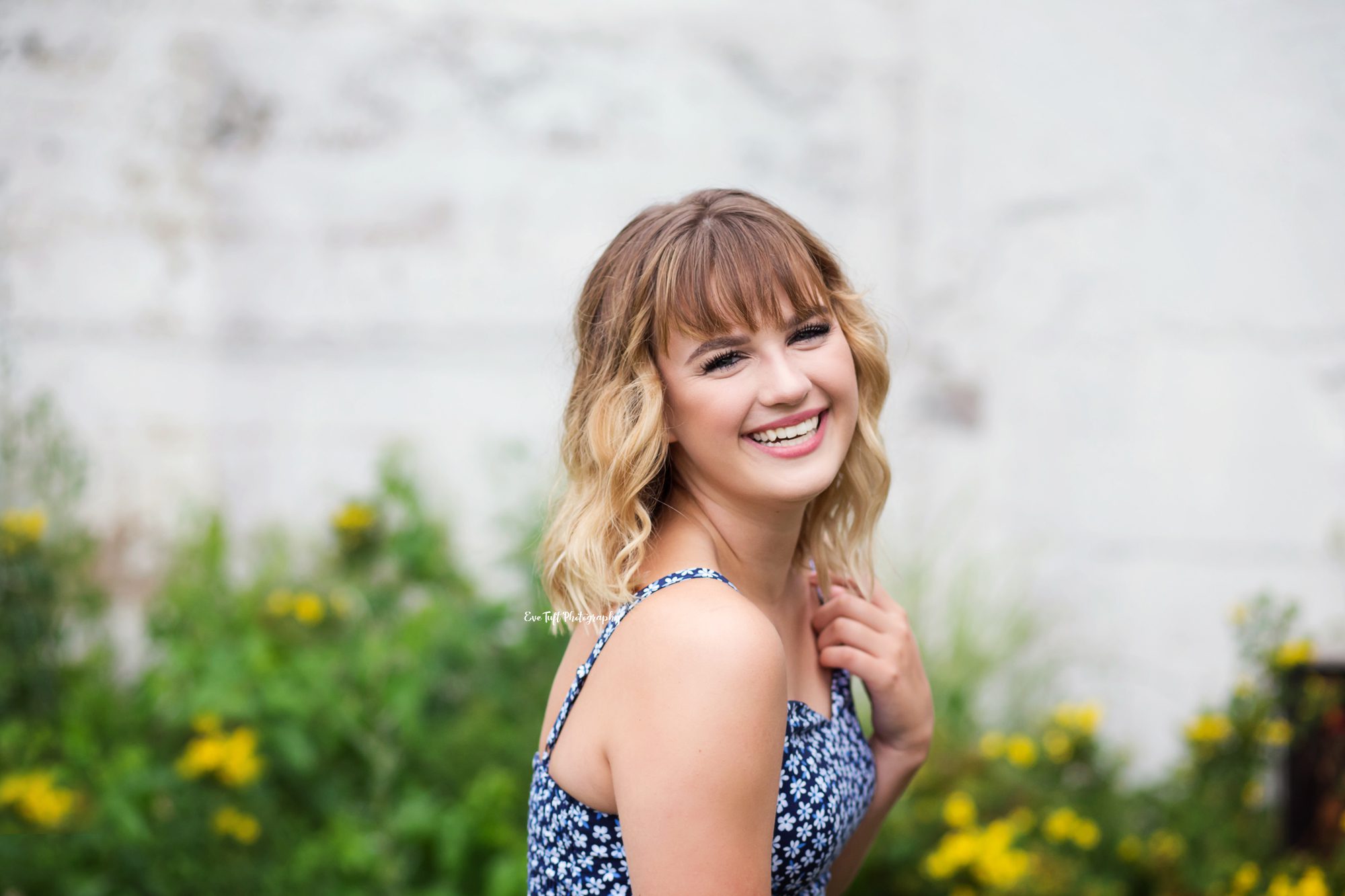Senior girl in front of a wall laughing at the camera | Photographer in Midland, MI