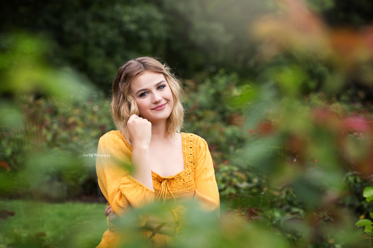 Senior girl softly smiling at Dow Gardens in the rose garden for her photo shoot | Michigan senior portraits