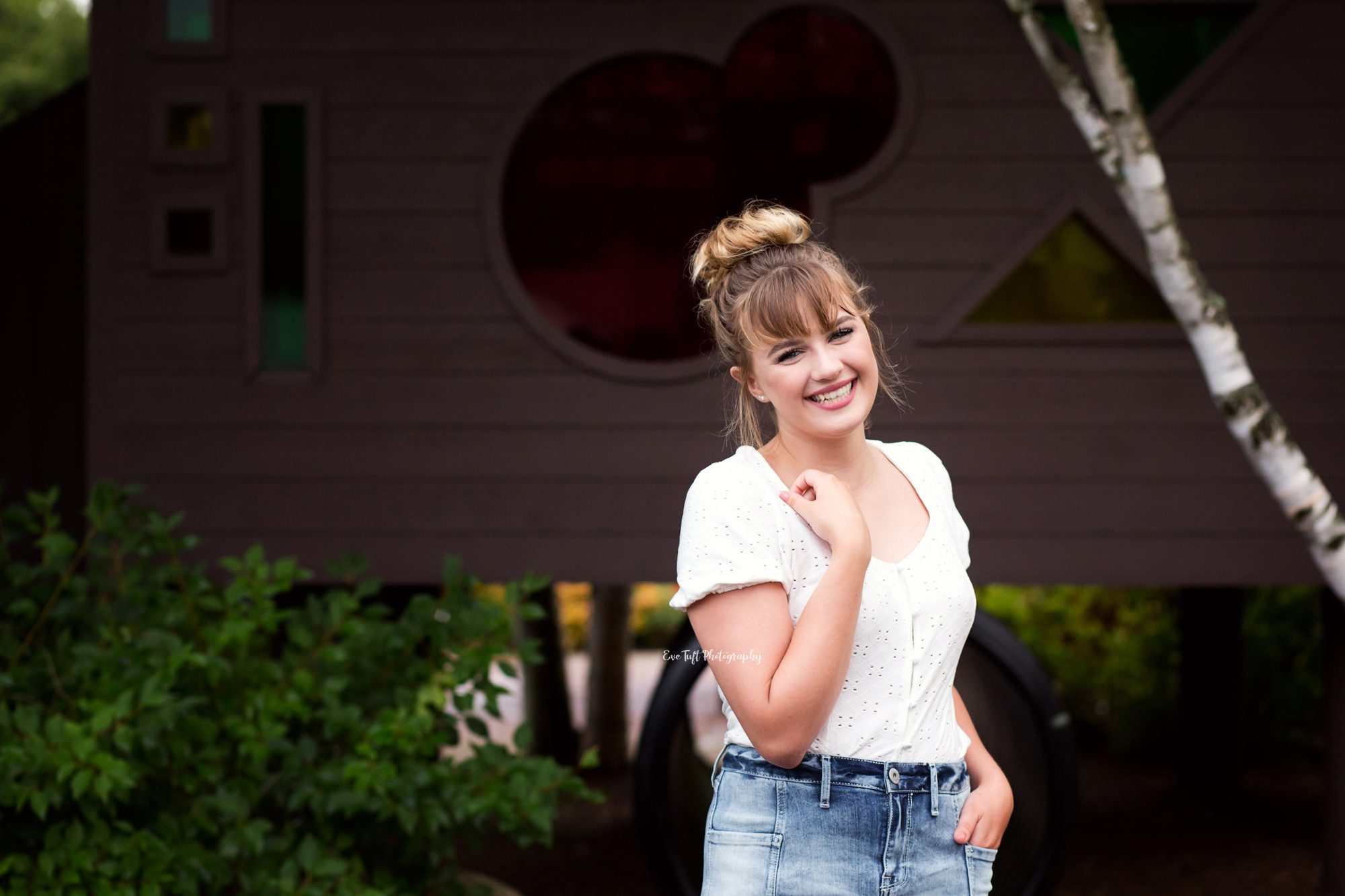 High School Senior girl standing in front of a tree house and smiling | Senior pictures by Eve Tuft Photography
