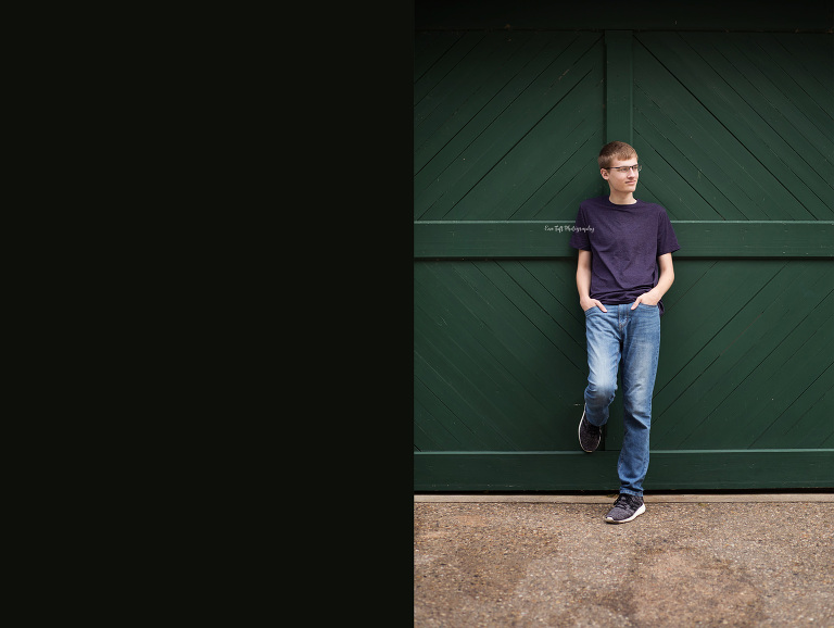 Snior guy leaning against a green barn door at Dow Gardens | Senior Portraits in Michigan