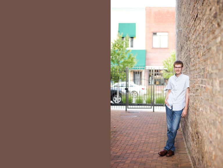 A senior boy leans up against a wall in an urban setting downtown | Senior Photographer in Midland, Michigan