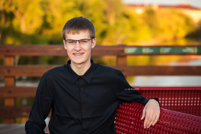 Senior boy sitting on a red bench on the Tridge in Michigan | Midland Senior Pictures