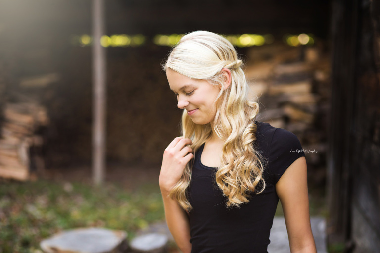 Teenage girl holding onto her hair and looking down while smiling outside | Senior Photographer in Midland, Michigan