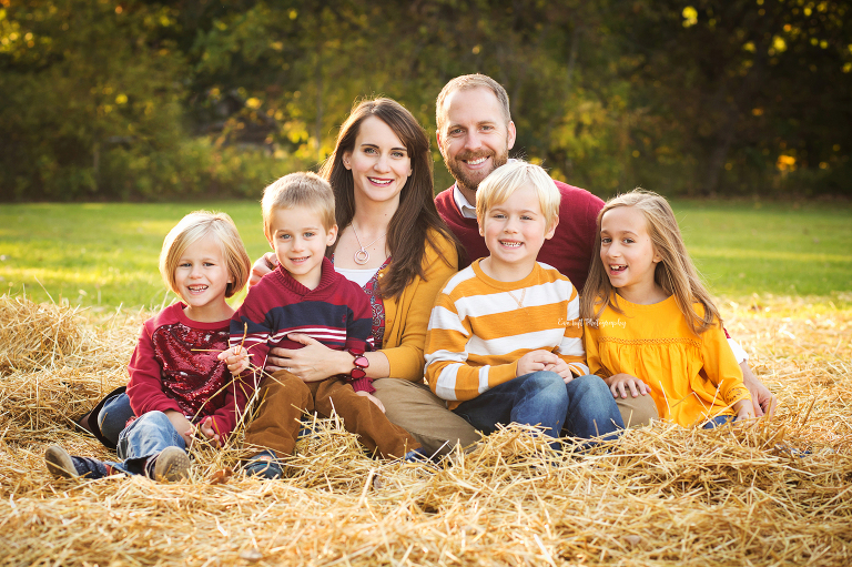 A family of six sits in some straw in a field outdoors | Family pictures for Eve Tuft Photography